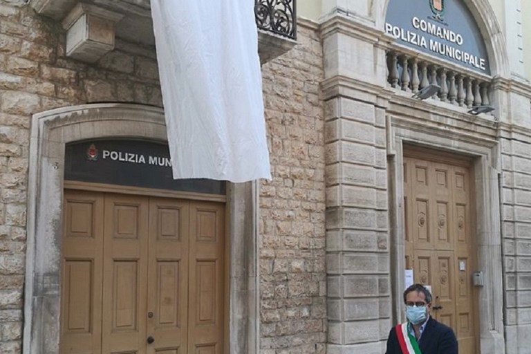 Lenzuolo bianco sul balcone della sede della Polizia Locale