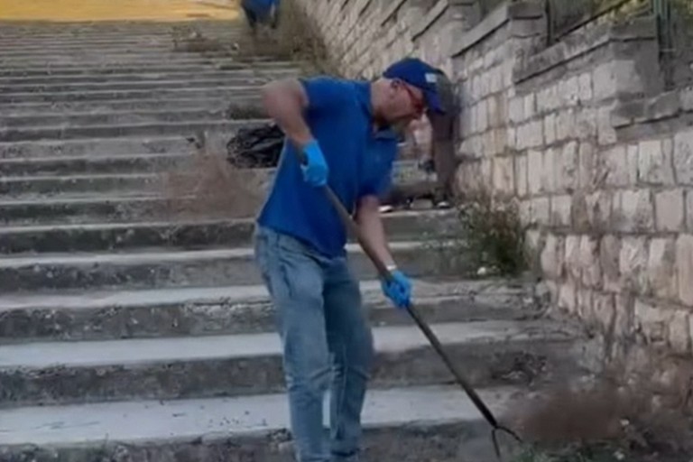 I collaboratori delle Vecchie Segherie Mastrototaro ripuliscono la scalinata di via Porto